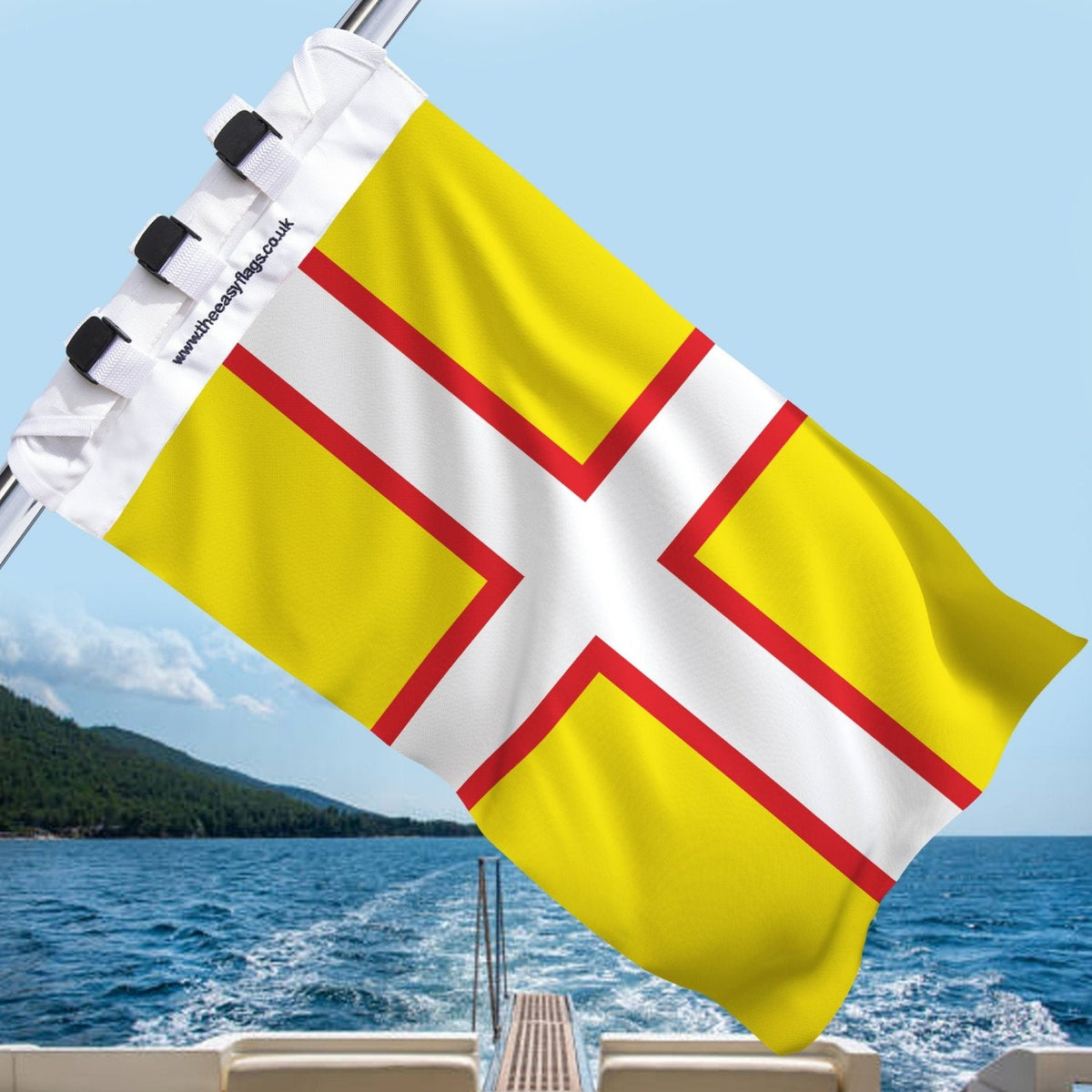Dorset county flag with red cross outlined in gold on white background, mounted on a boat rail with a universal triple-lock system, flying at sea with blue sky and coastline in the background
